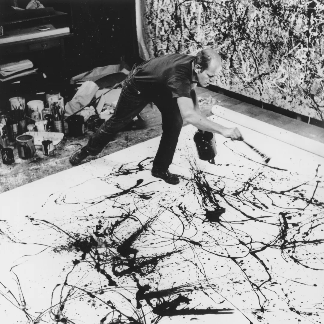 Jackson Pollock w trakcie pracy nad obrazem, maluje na podłodze rozlewając i chlapiąc farbą.